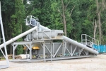 Olympus SludgePUG Pugmill system by PavementGroup.com shown set up with sludge bin, incline bin, pugmill and silo